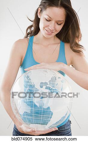 Stock Photography - Mixed race woman holding inflatable globe. Fotosearch
