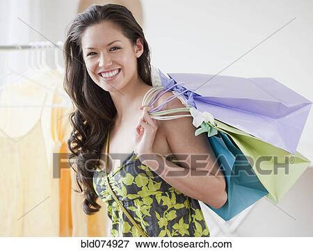Stock Photo - Mixed race woman holding shopping bags. Fotosearch