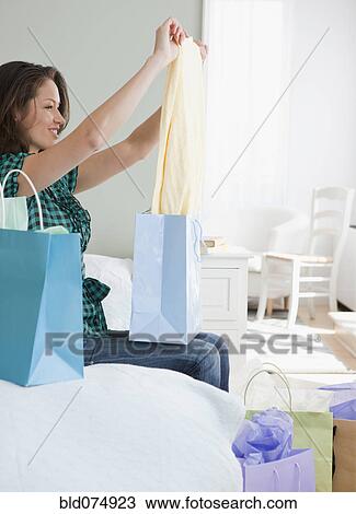 Mixed race woman pulling clothes from shopping bags View Large Photo Image Stock Image - Mixed race woman pulling clothes from shopping bags. Fotosearch