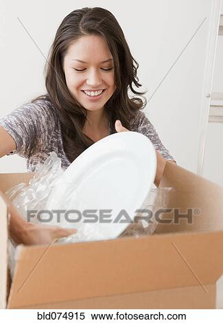 Stock Photography - Mixed race woman unpacking dishes. Fotosearch