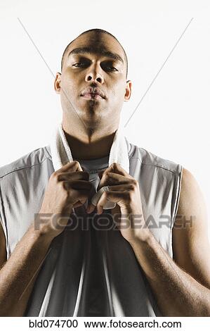 Stock Image - Serious African man holding towel around neck. Fotosearch