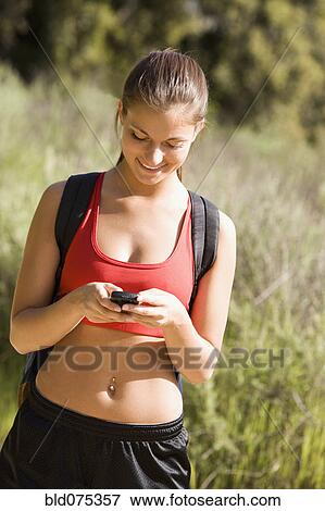 Stock Photo - Smiling Hispanic woman looking at cell phone. Fotosearch