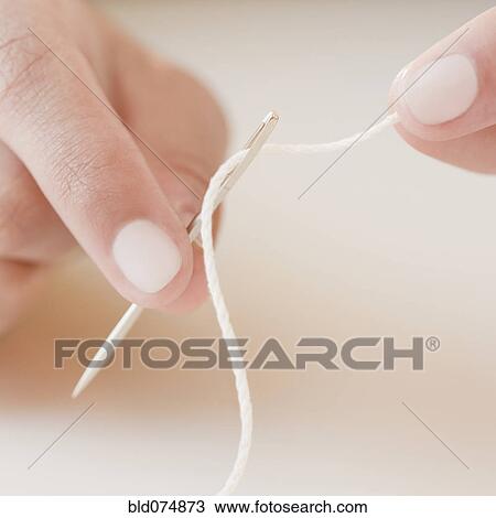 Stock Image - Woman threading needle. Fotosearch