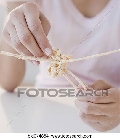 Picture - Woman tying knot in rope. Fotosearch
