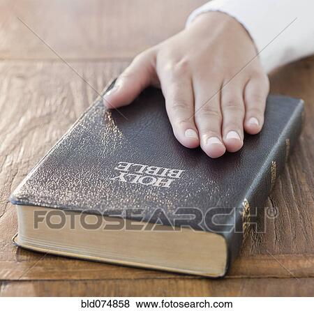 Stock Photo - Woman's hand on Bible. Fotosearch