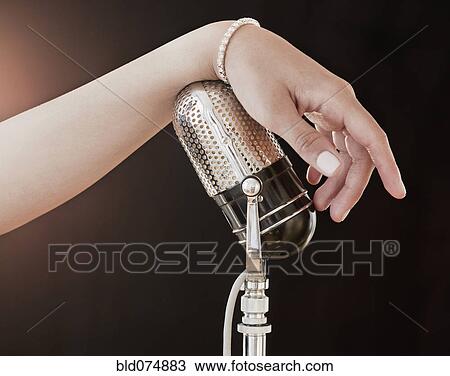 Stock Image - Woman's hand on retro microphone. Fotosearch
