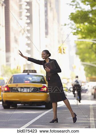 Stock Image - African businesswoman hailing taxi. Fotosearch