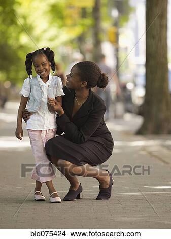 Picture - African businesswoman hugging girl. Fotosearch