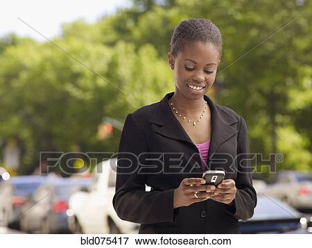 African businesswoman looking down at cell phone View Large Photo Image Stock Photo - African businesswoman looking down at cell phone. Fotosearch