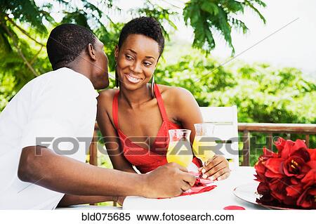 Stock Photography - African couple drinking orange juice on patio. Fotosearch