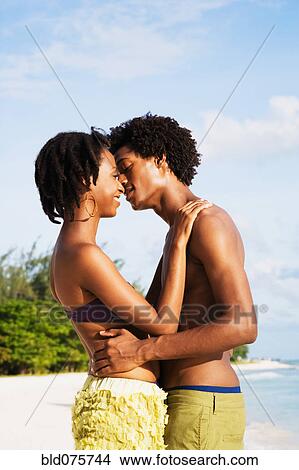 Picture - African couple kissing on beach. Fotosearch