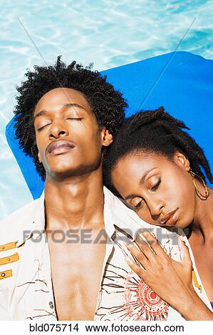 Picture - African couple laying in sun with eyes closed. Fotosearch