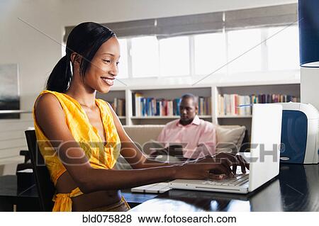 African couple reading and using laptop in living room View Large Photo Image Stock Photo - African couple reading and using laptop in living room. Fotosearch