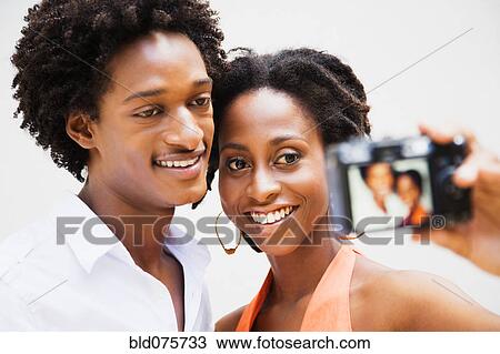 Stock Image - African couple taking self-portrait with digital camera. Fotosearch