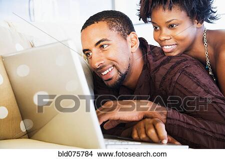 African couple using laptop on sofa View Large Photo Image Picture - African couple using laptop on sofa. Fotosearch