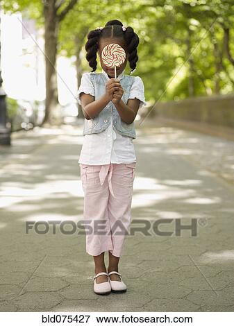 Stock Photo - African girl hiding behind lollipop. Fotosearch