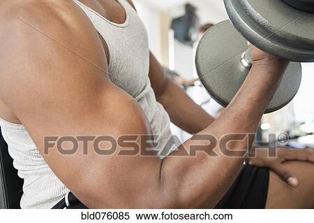 Stock Photography - African man doing biceps curls with dumbbell. Fotosearch