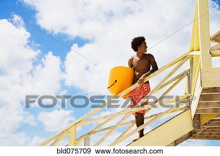 African man holding body board on lifeguard hut ramp View Large Photo Image Stock Photo - African man holding body board on lifeguard hut ramp. Fotosearch