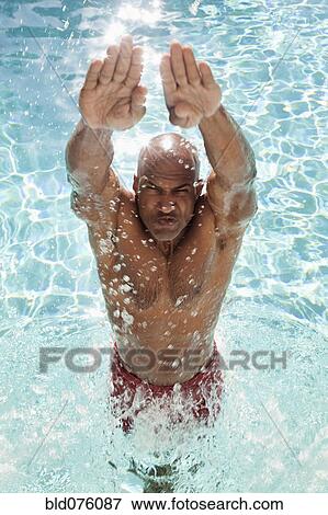 Stock Photo - African man jumping out of swimming pool. Fotosearch