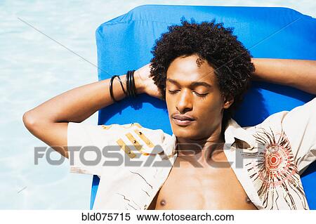 Stock Photography - African man laying in sun with eyes closed. Fotosearch