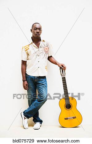 Stock Photo - African man leaning on guitar. Fotosearch