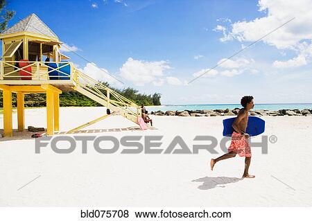 African man running with body board on beach View Large Photo Image Stock Photo - African man running with body board on beach. Fotosearch