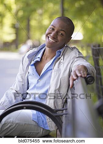 Stock Photography - African man smiling on bench. Fotosearch