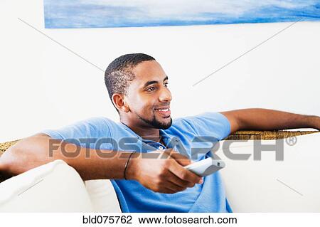 Stock Image - African man watching television. Fotosearch