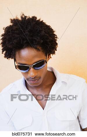Stock Image - African man wearing sunglasses and looking down. Fotosearch