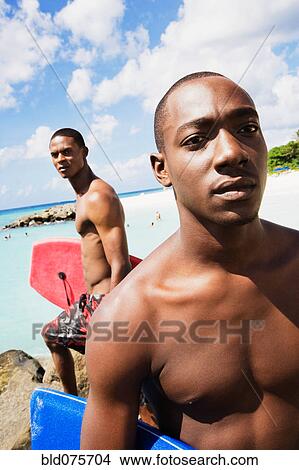 African men holding body boards on beach View Large Photo Image Picture - African men holding body boards on beach. Fotosearch