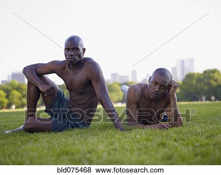Stock Photo - African men laying in grass at park. Fotosearch