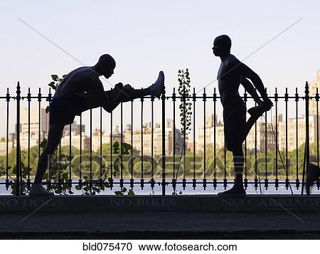 Stock Image - African men stretching on railing. Fotosearch