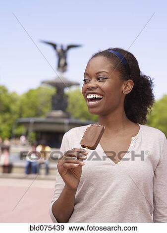 Stock Photo - African woman eating ice cream bar. Fotosearch