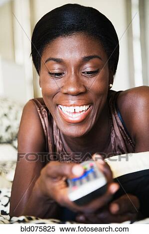 Stock Photography - African woman holding remote control. Fotosearch