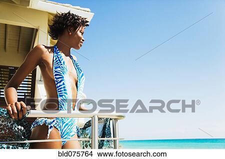 African woman in bathing suit on balcony looking at ocean View Large Photo Image Picture - African woman in bathing suit on balcony looking at ocean. Fotosearch
