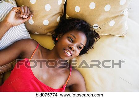 Picture - African woman laying on bed. Fotosearch
