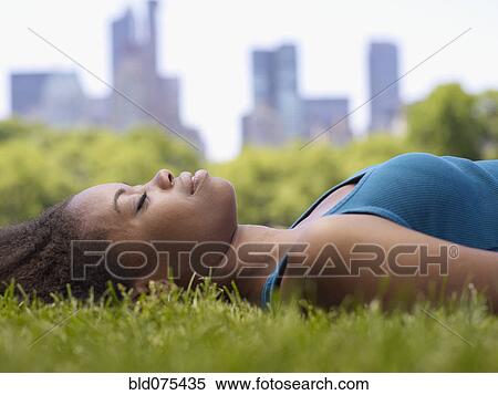 African woman laying on grass in park View Large Photo Image Stock Photography - African woman laying on grass in park. Fotosearch
