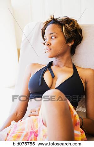 Stock Photography - African woman laying on lounge chair. Fotosearch