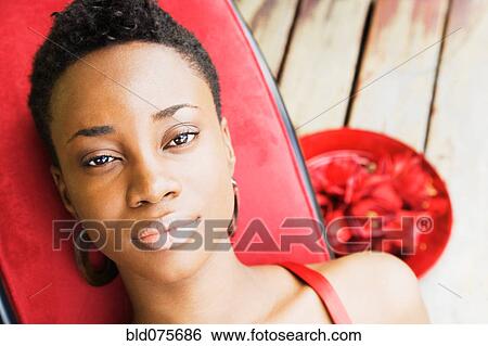 Stock Photograph - African woman on lounge chair. Fotosearch