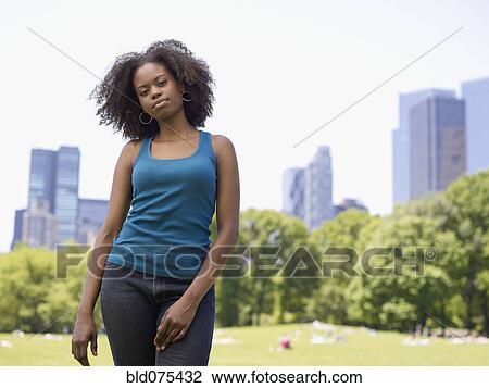Stock Image - African woman standing in park. Fotosearch
