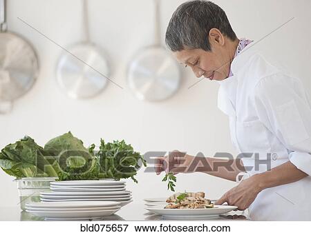 Stock Photo - Chinese chef plating meals in professional kitchen. Fotosearch