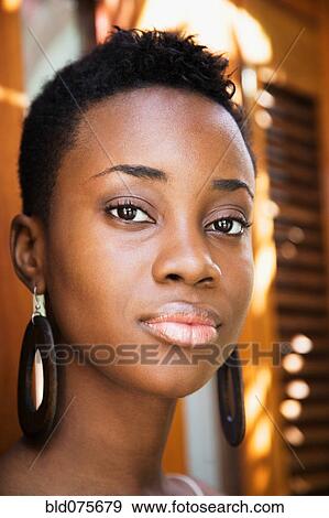 Stock Photo - Close up of African woman wearing wooden earrings. Fotosearch