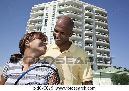 Stock Photo - Couple holding tennis racket and smiling. Fotosearch