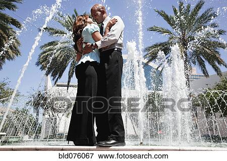 Couple hugging and kissing at fountain View Large Photo Image Stock Photo - Couple hugging and kissing at fountain. Fotosearch