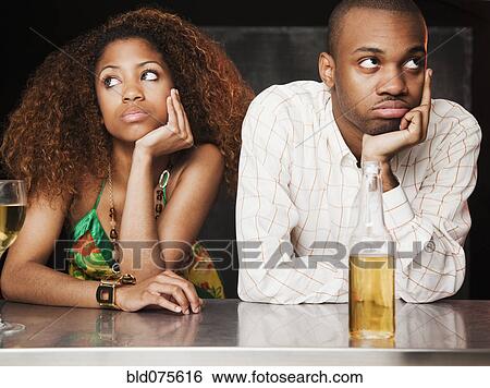 Stock Photograph - Couple sitting at bar and looking irritated. Fotosearch