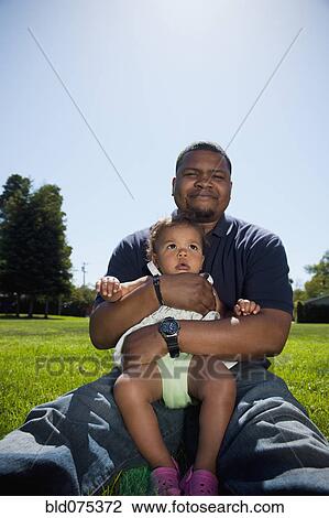 Stock Image - Father holding daughter in park. Fotosearch