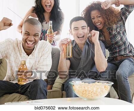 Stock Image - Friends drinking beer and watching football on television. Fotosearch