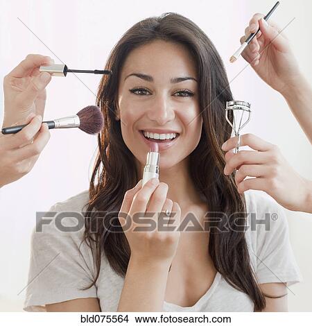 Picture - Hands applying makeup to Hispanic woman's face. Fotosearch