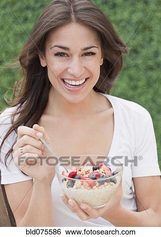 Stock Photograph - Hispanic woman eating cereal with fresh fruit. Fotosearch
