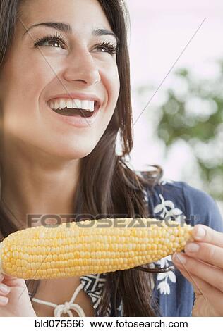 Stock Photograph - Hispanic woman eating ear of corn. Fotosearch